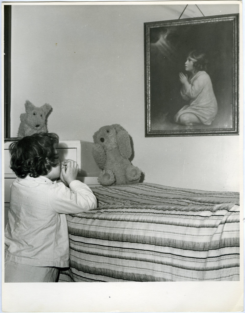 Child praying beside their bed