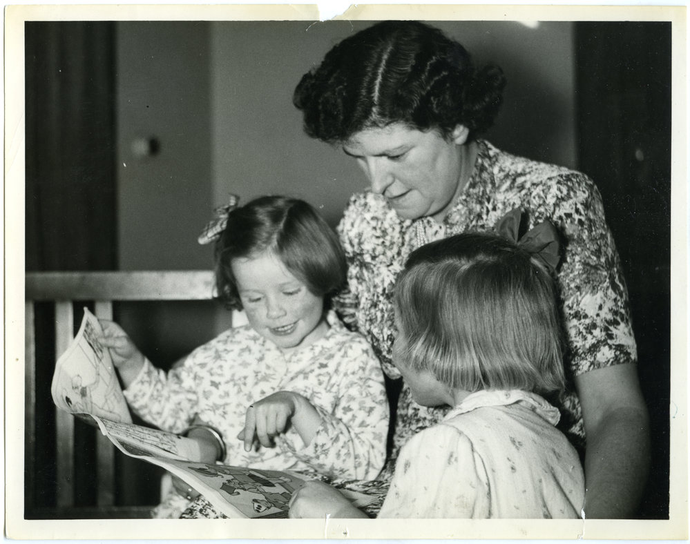 Residents of Nisbett Cottage, Glendining Home are read a bedtime story by Miss Halies, 1955