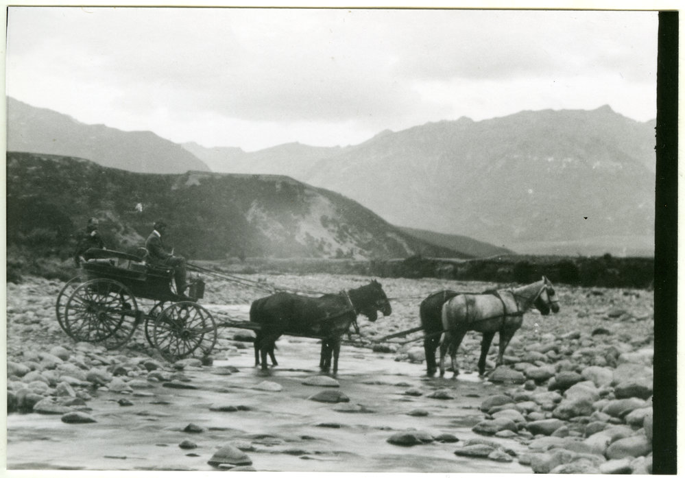 Four horses pull a coach through a stream
