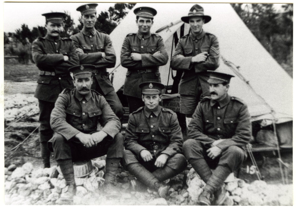 Seven soldiers posing in front of a tent