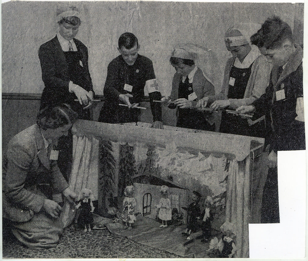 Unidentified women and children stand around a puppet show