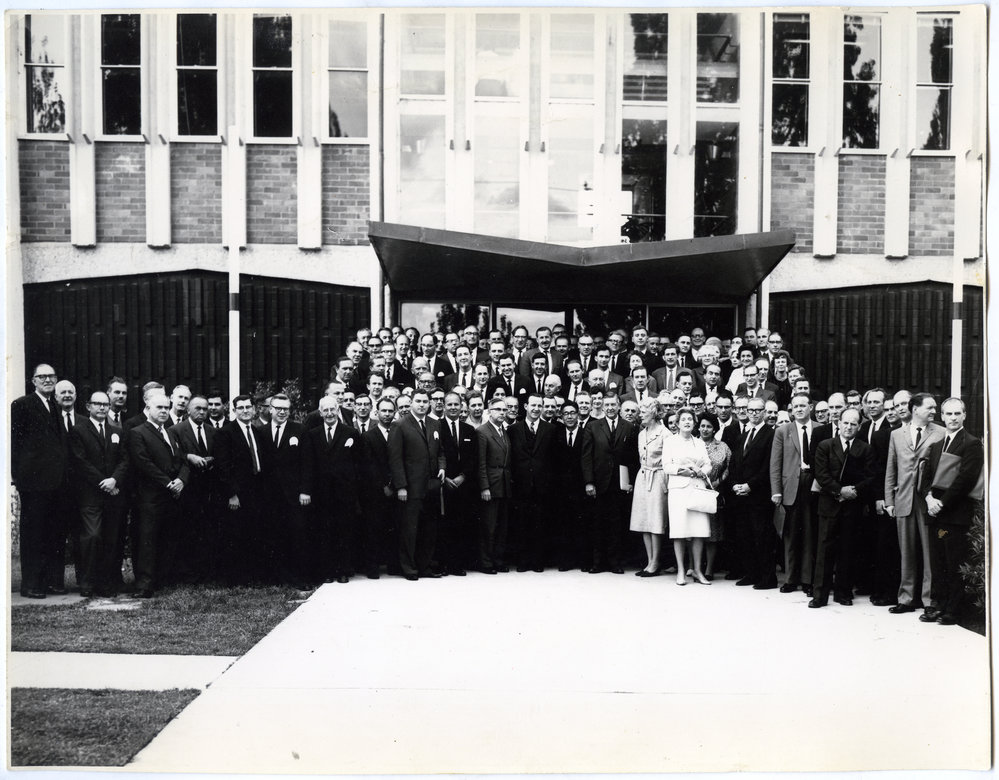 Large group of unidentified individuals standing in front of a brick building