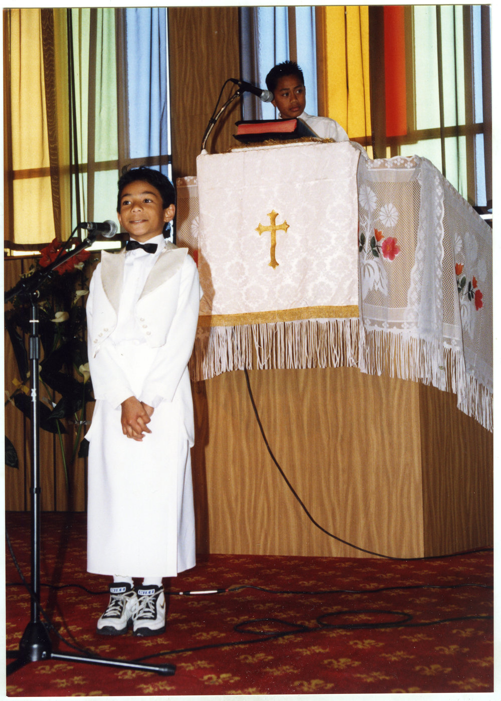 Young boy speaks into a microphone, whilst another stands at the pulpit and Glen Eden Pacific Islanders Church during a White Sunday service, 2002