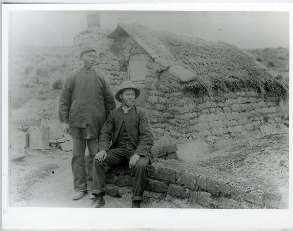 Rev.  Alexander Don and Tse Yuan Bor sitting outside a clay brick hut