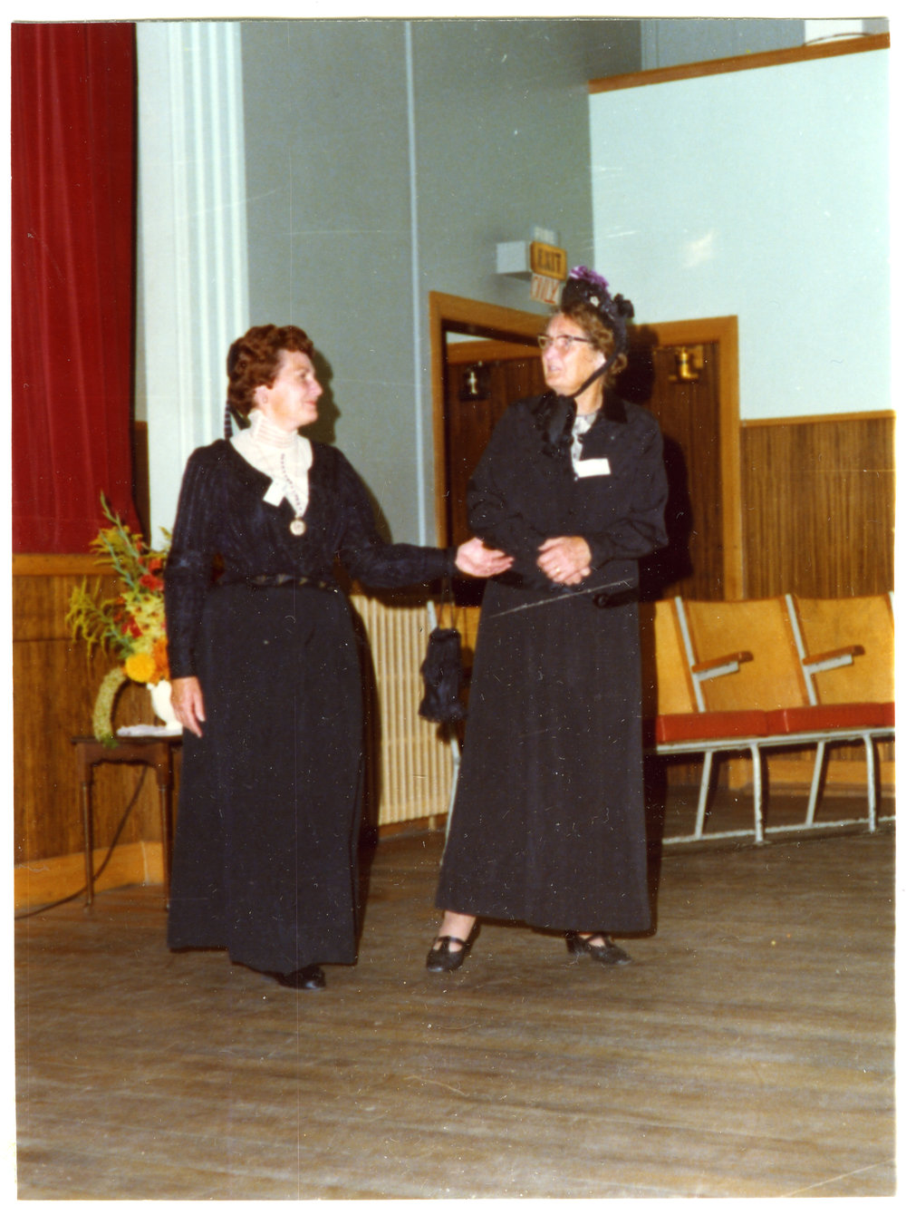 Two women stand in a sports gymnasium wearing period clothing, Cromwell Church