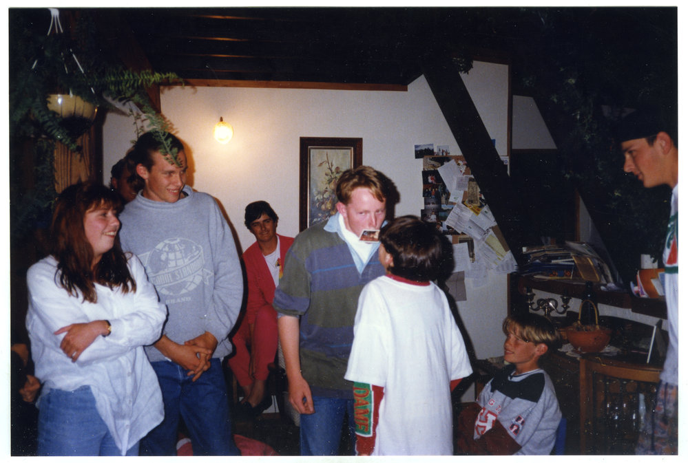 Two boys pass each other a playing card during a game at the Youth With A Mission evening, a group of young men and woman look on
