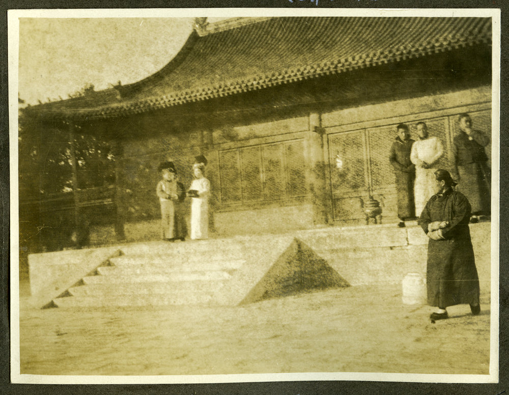 "Hall of Agriculture," unidentified individuals stand outside a low building 