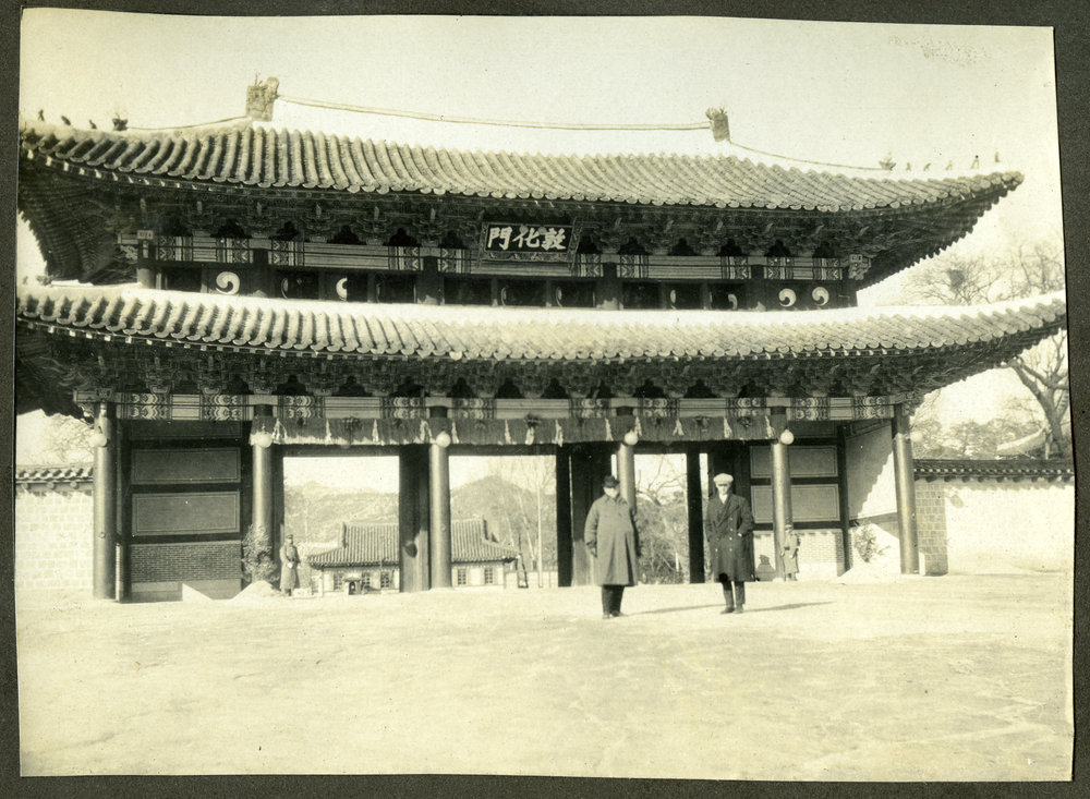 Reverend Profession W. Hewitson standing in front of and ornamental gateway