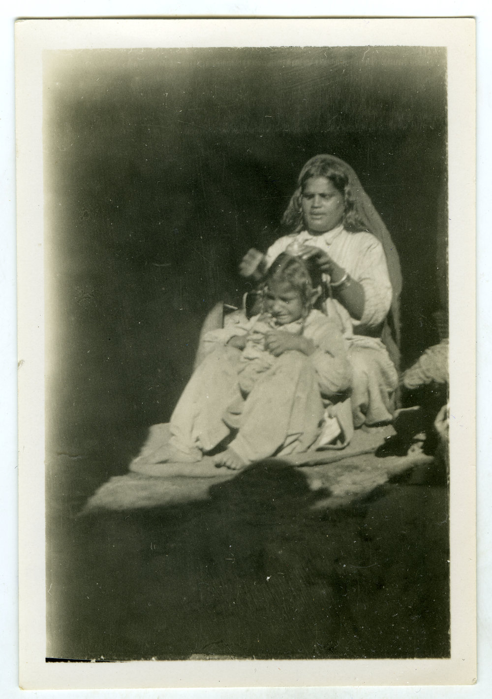 Unidentified Sikh woman styling an identified child's hair