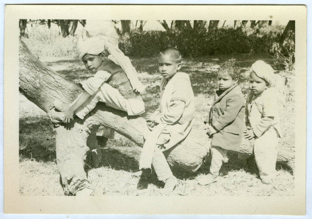 Four unidentified children sitting on a log