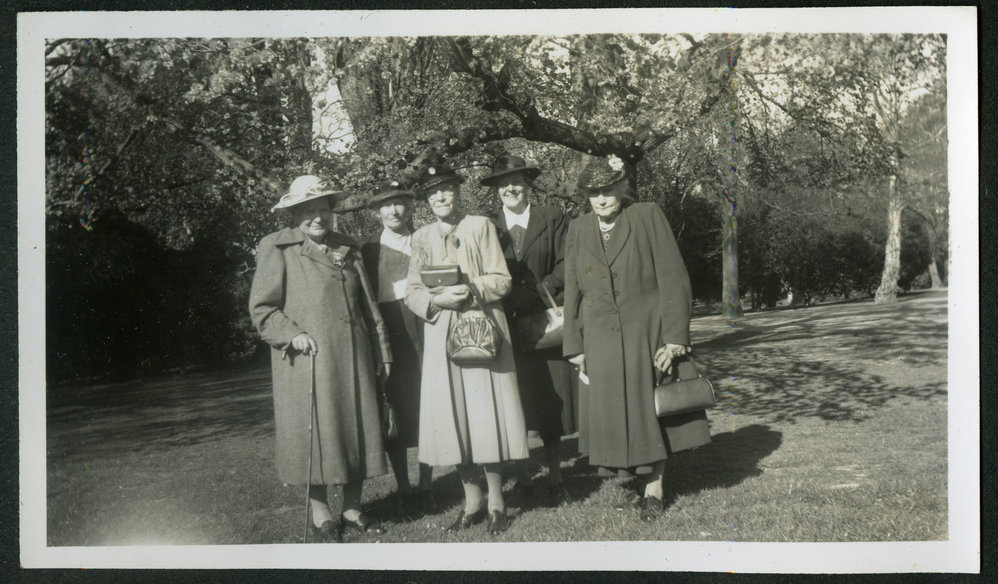 Five unidentified women standing in a park, dressed in woolen coats 