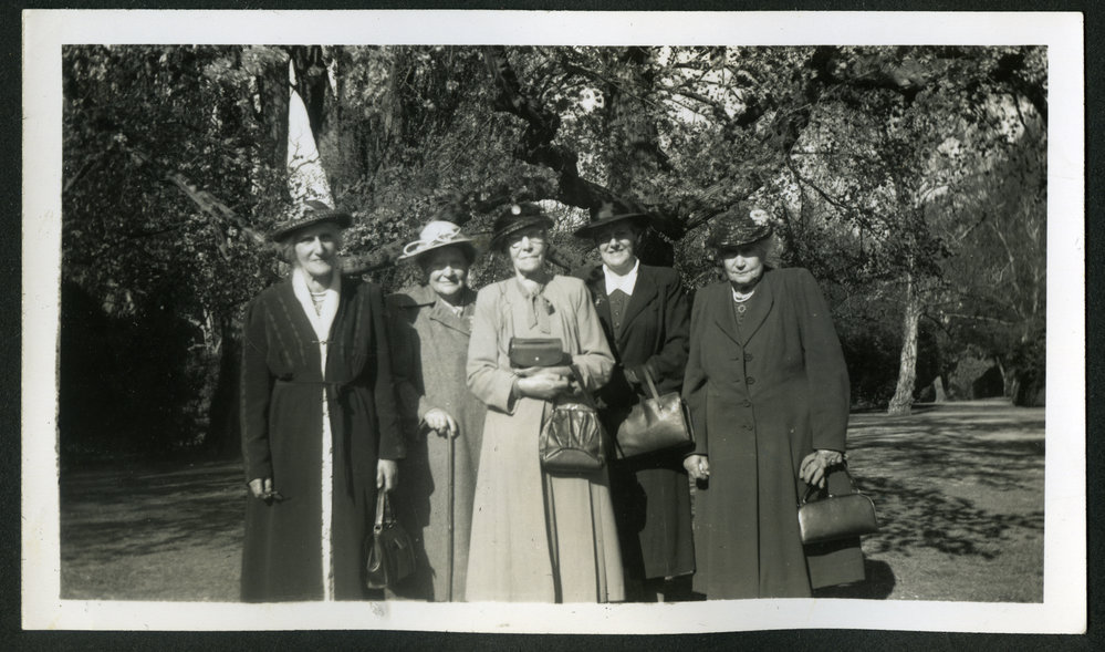Five unidentified women standing in a park, dressed in woolen coats