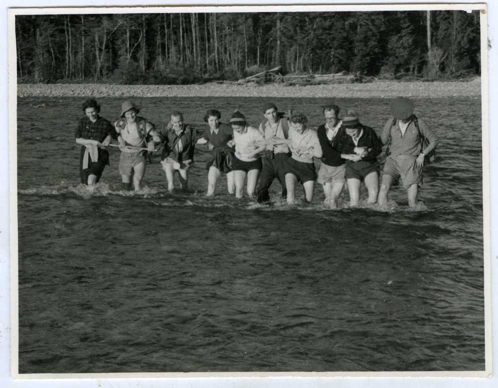 Unidentified group of women and men cross a river