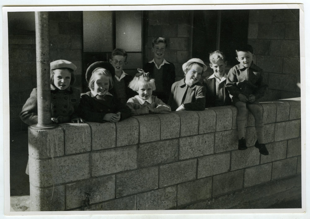 Unidentified girls stand by a brick wall, St. Enoch's, Christchurch