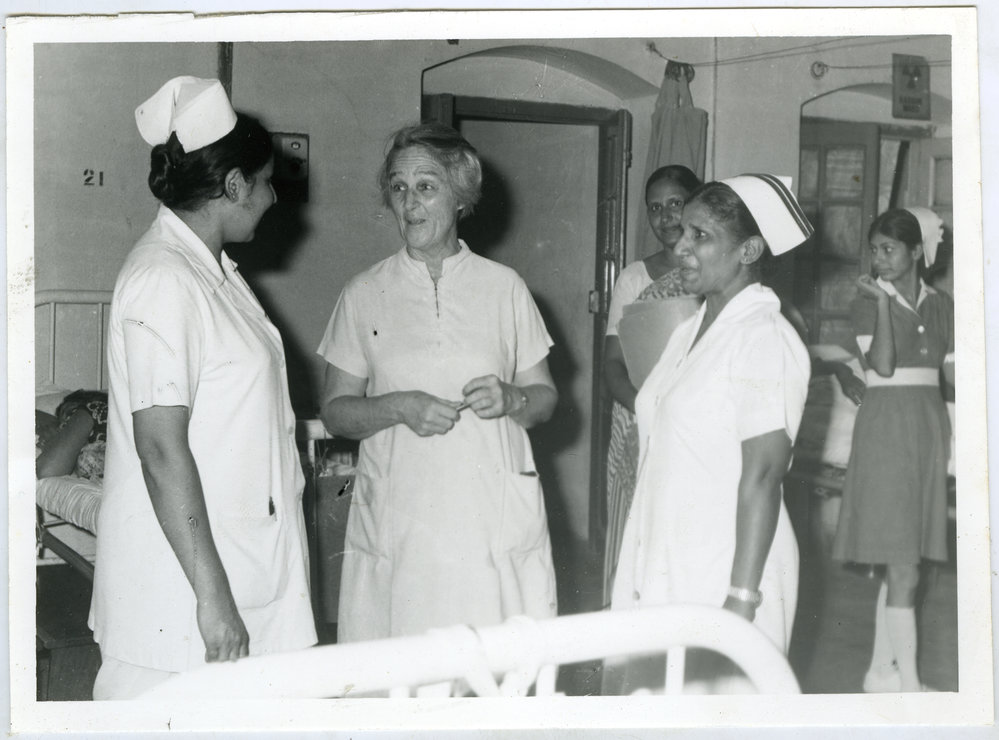 Beryl Howie is talking to two unidentified Indian nurses, another unidentified Indian nurse is in the background with a patient