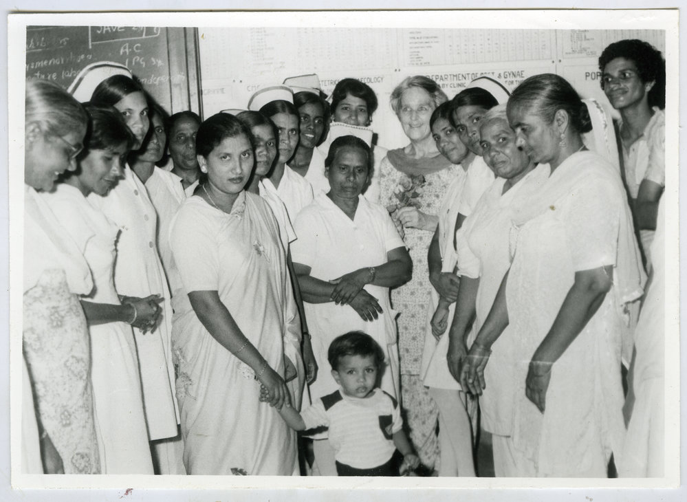 An unidentified child is photograph surrounded by unidentified female nurses and patients