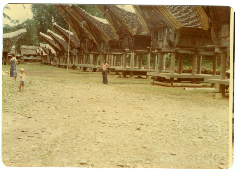 Johanes Rante Banu in Front of a Row of Rice Storehouses (("lumbubg") at Kete