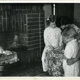'Storytime is bedtime,' residents of Nisbet Cottage, Glendining Home are read a bedtime story by Miss Halies, 1955