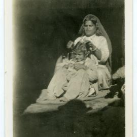 Unidentified Sikh woman styling an identified child's hair