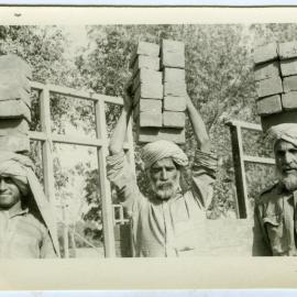 Workmen carrying bricks