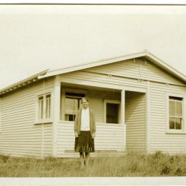 Sister Dorothy Keen (Mrs. Page) standing in front of wooden building