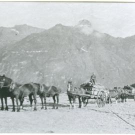 Horses pull carts by a river