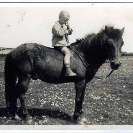 Unidentified young boy rides a horse