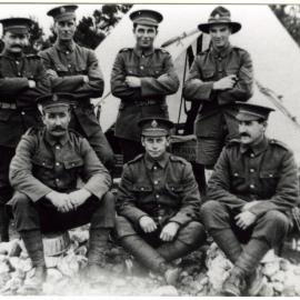 Seven soldiers posing in front of a tent