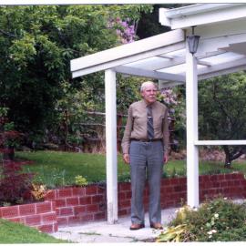Unidentified man stands under a verandah