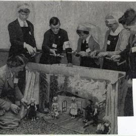Unidentified women and children stand around a puppet show