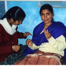 Two young women are learning the art of needlework