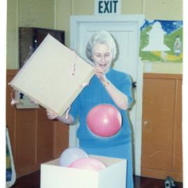 Rosemary Harris opening a box of blue and pink balloons 