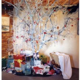 Silver Christmas tree, decorated with red baubles and presents