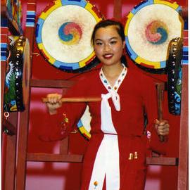 A young woman dressed in red plays traditional drums, General Assembly 2002