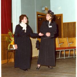Two women stand in a sports gymnasium wearing period clothing, Cromwell Church