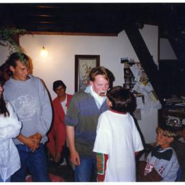 Two boys pass each other a playing card during a game at the Youth With A Mission evening, a group of young men and woman look on