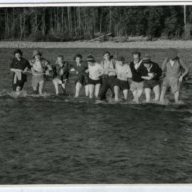 Unidentified group of women and men cross a river