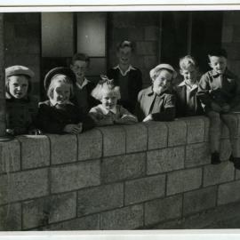 Unidentified girls stand by a brick wall, St. Enoch's, Christchurch