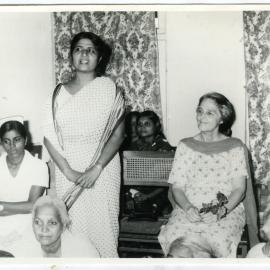 Beryl Howie is seated with other Indian women, as an unidentified Indian stands, offering a speech, Ludhiana