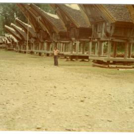 Johanes Rante Banu in Front of a Row of Rice Storehouses (("lumbubg") at Kete