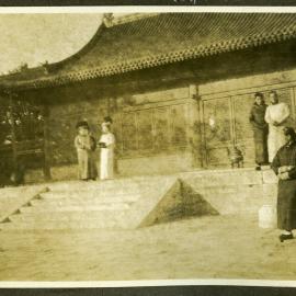 "Hall of Agriculture," unidentified individuals stand outside a low building 